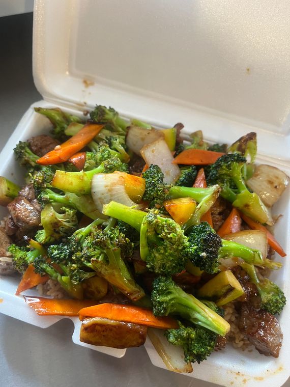 A styrofoam container filled with broccoli , carrots and meat.