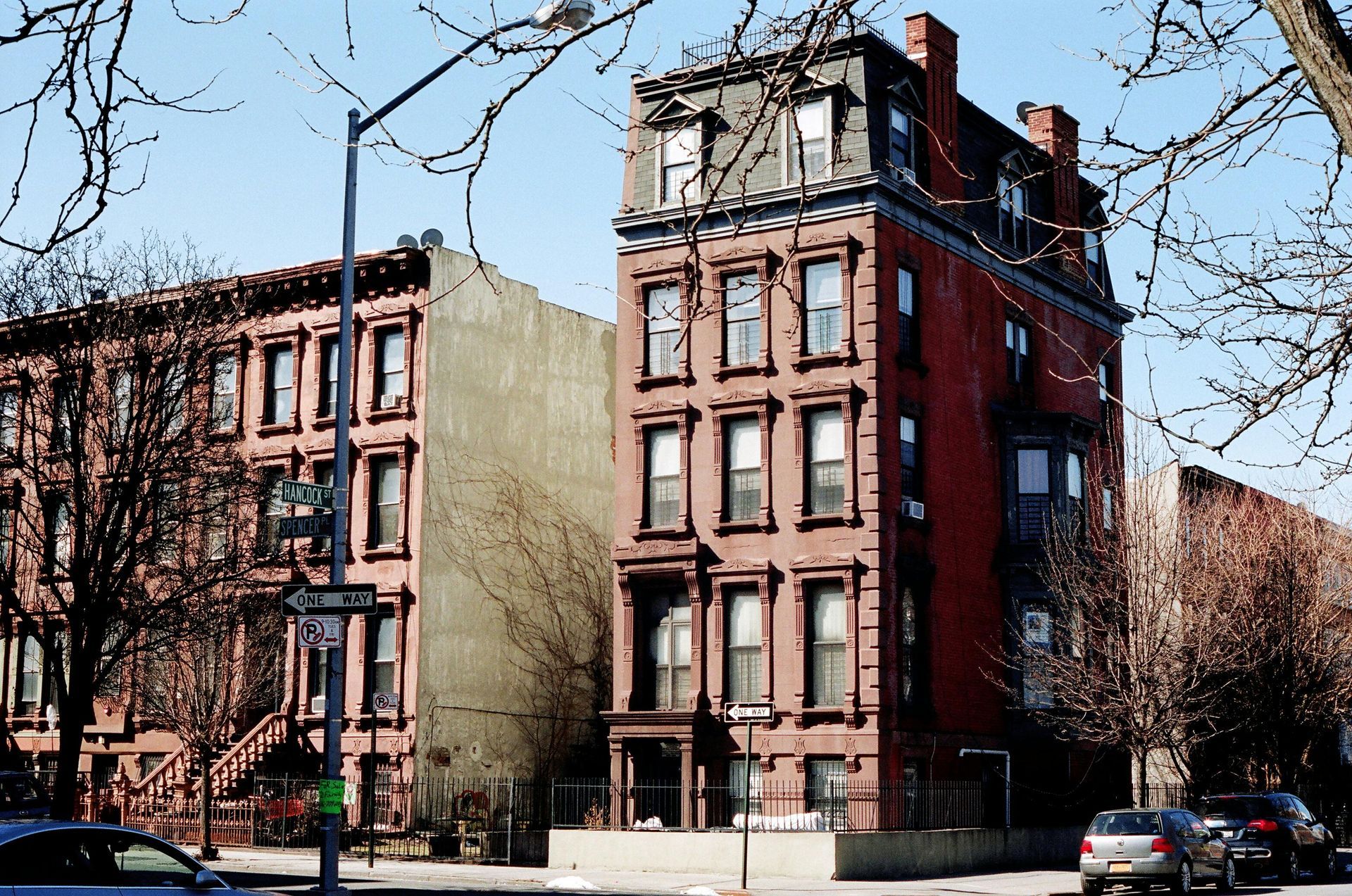 A row of brick buildings with cars parked in front of them