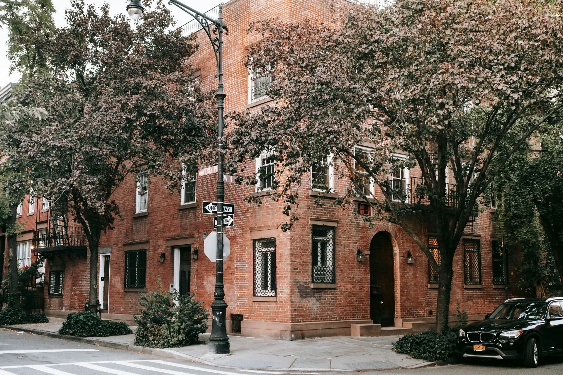 A car is parked on the side of the road in front of a brick building.