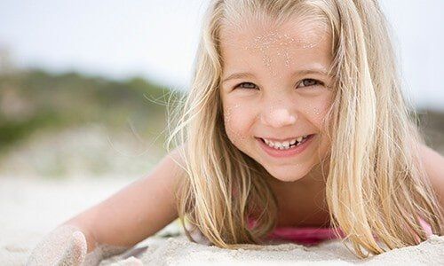 Young Girl Smiling in Sand - Oral Health in Pleasant Hill, MO