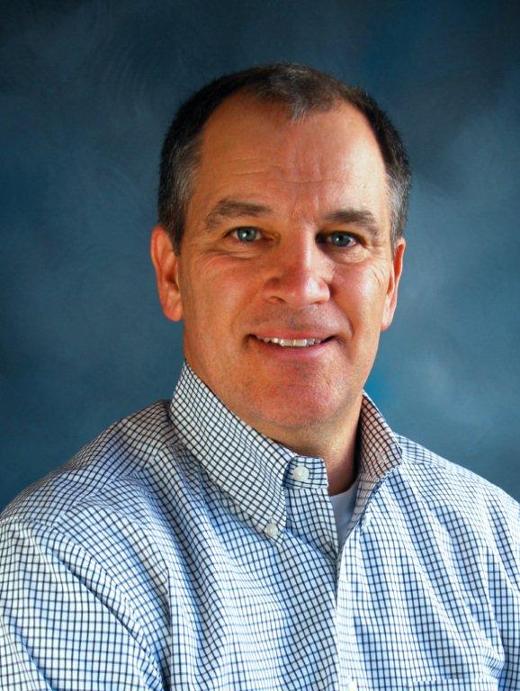 A man in a plaid shirt is smiling for the camera