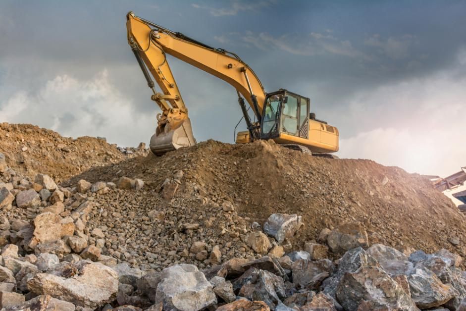 A Yellow Excavator is Sitting on Top of a Pile of Rocks — Zappala Quarries in Gordonvale, QLD