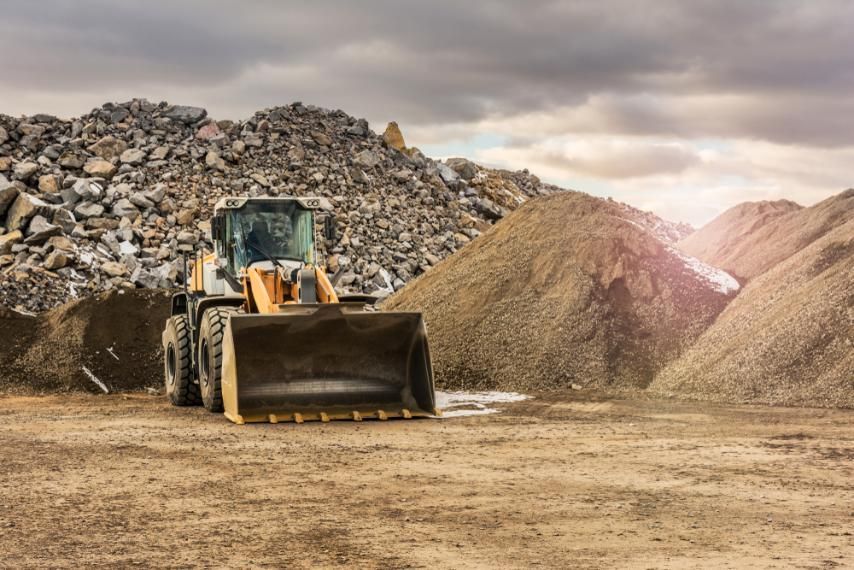 A Bulldozer is Driving Through a Dirt Field in Front of a Pile of Rocks — Zappala Quarries in Cairns, QLD