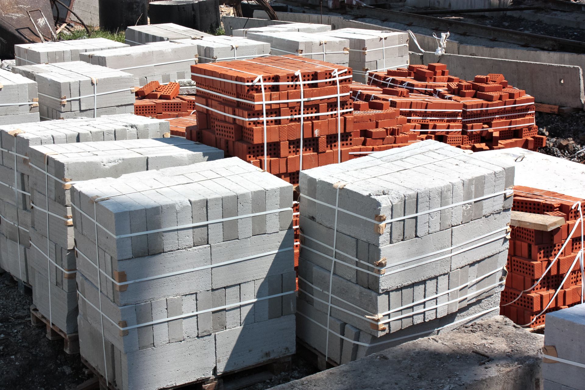 Stacks of Gray Cinder Blocks and Red Bricks Wrapped in White Twine, Outdoors — Zappala Quarries in Tully, QLD
