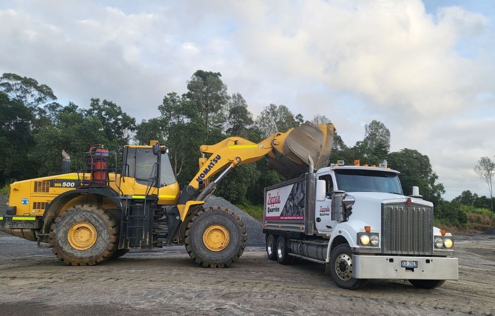 A Bulldozer Is Loading Gravel Into a Conveyor Belt at A Construction Site — Zappala Quarries in Gordonvale, QLD