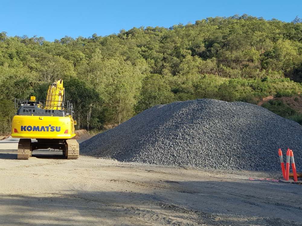 A Yellow Komatsu Excavator is Parked Next to a Pile of Gravel — Zappala Quarries in Gordonvale, QLD