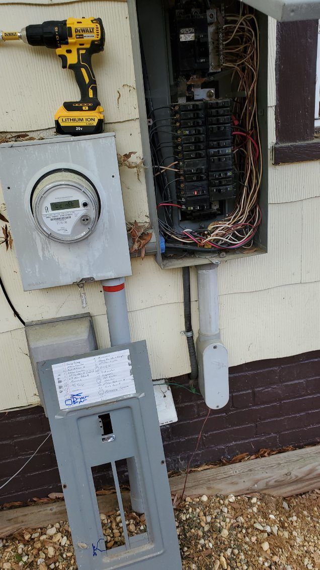 Exterior electrical panel open for repair, with a drill resting on top.