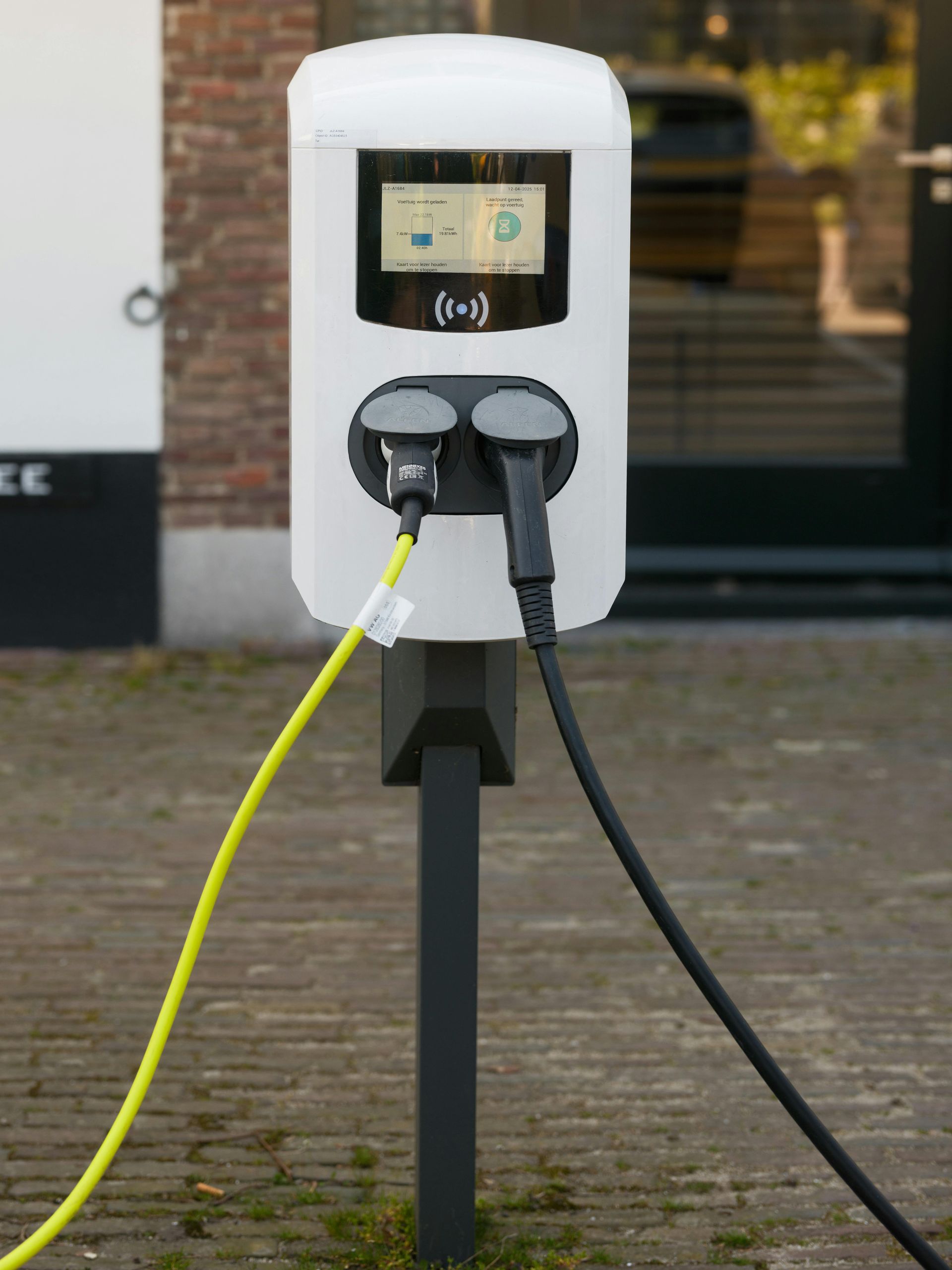 Electric vehicle charging station with yellow and black charging cables plugged in.