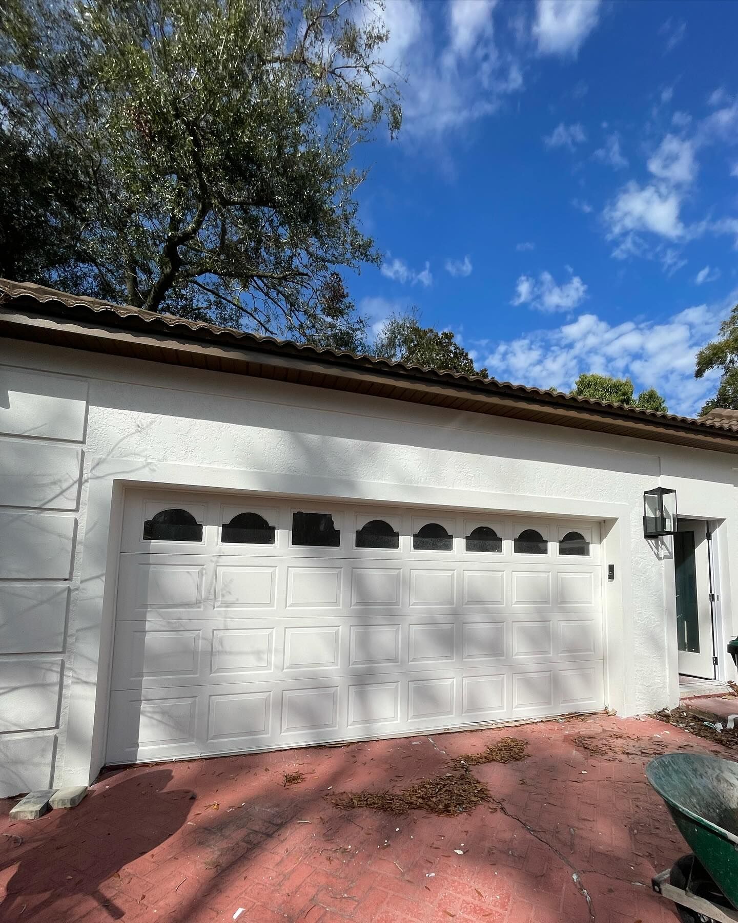A white garage door with a green wheelbarrow in front of it