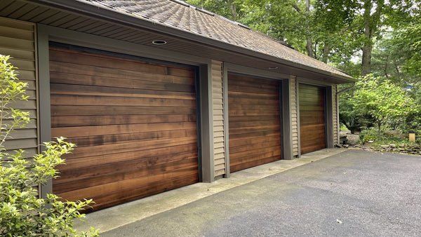 A garage with three wooden garage doors and a driveway.