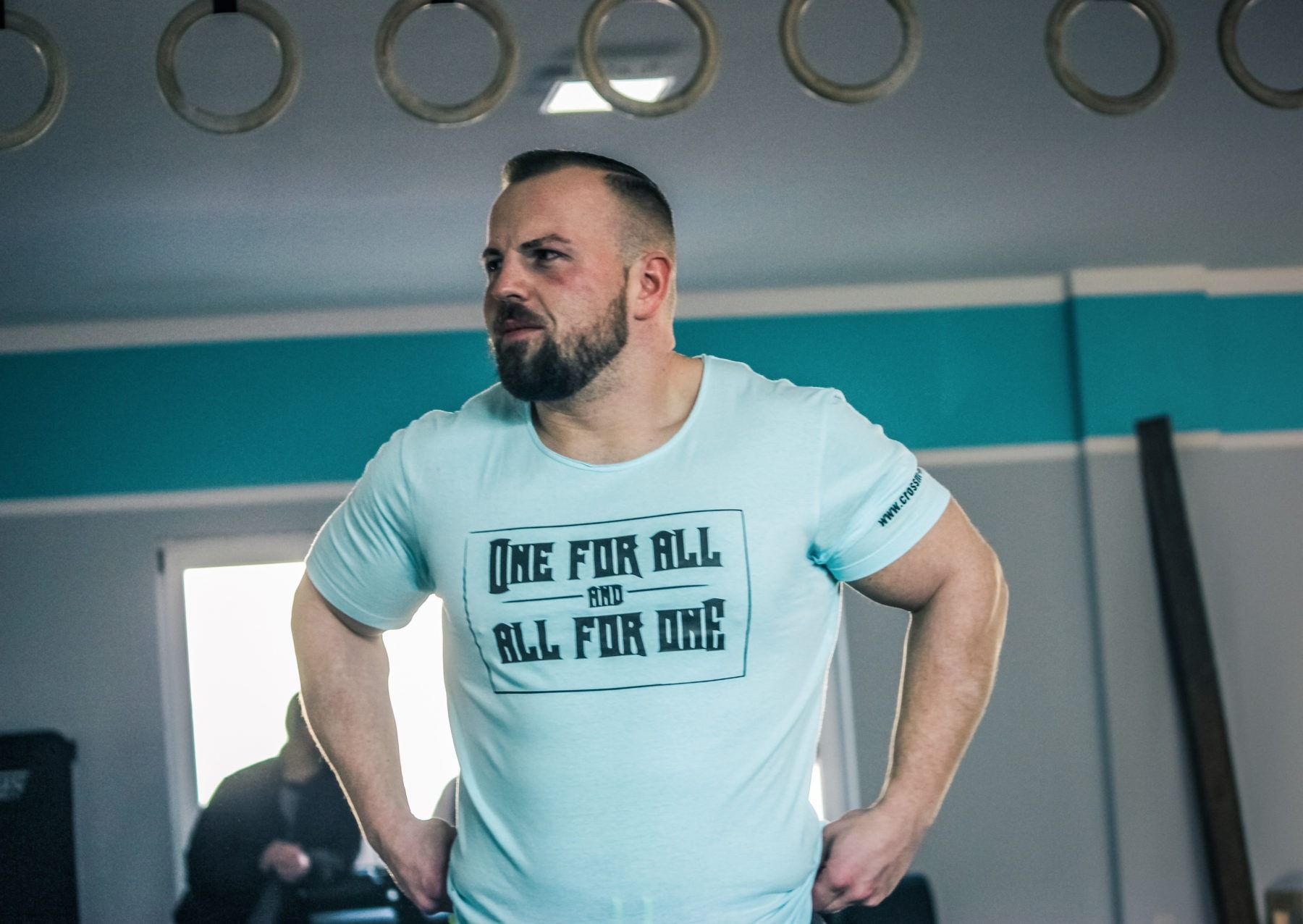 A bearded man in a light blue t-shirt with