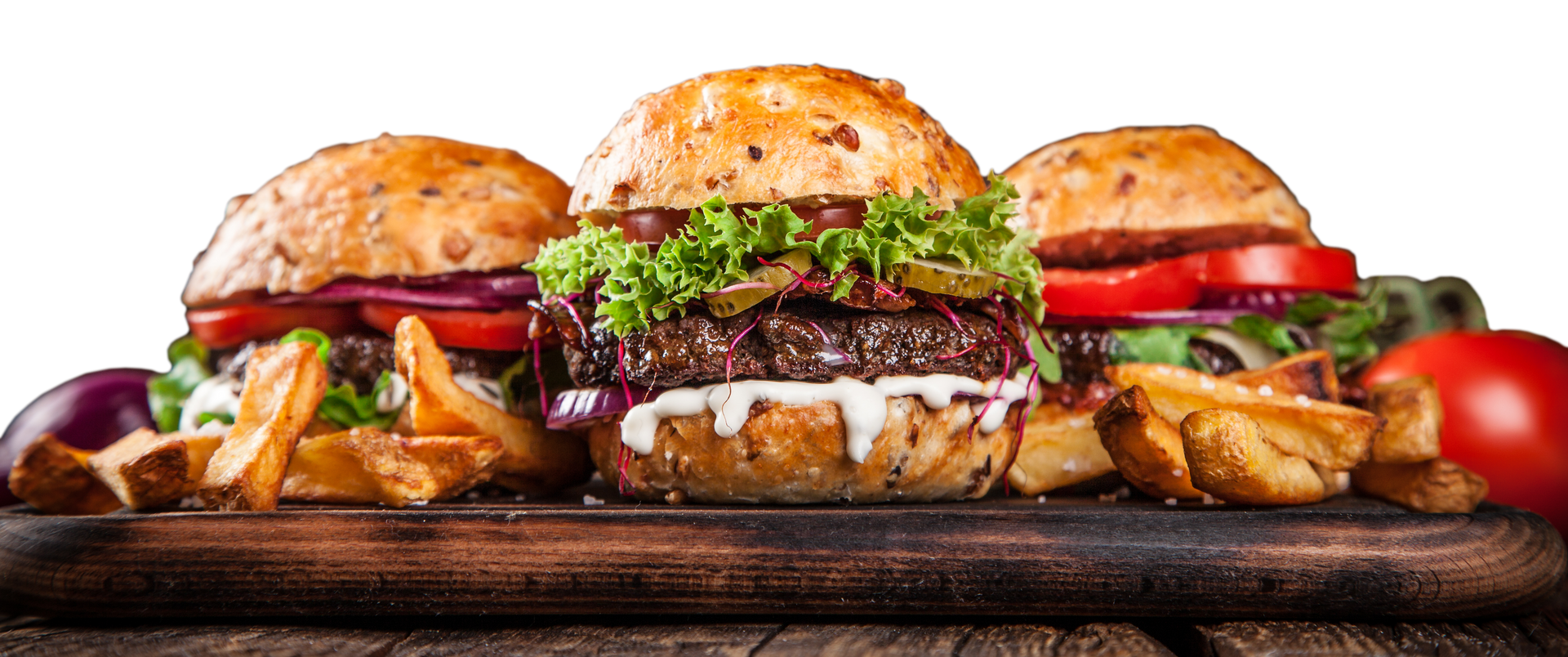 three hamburgers and french fries on a wooden cutting board .