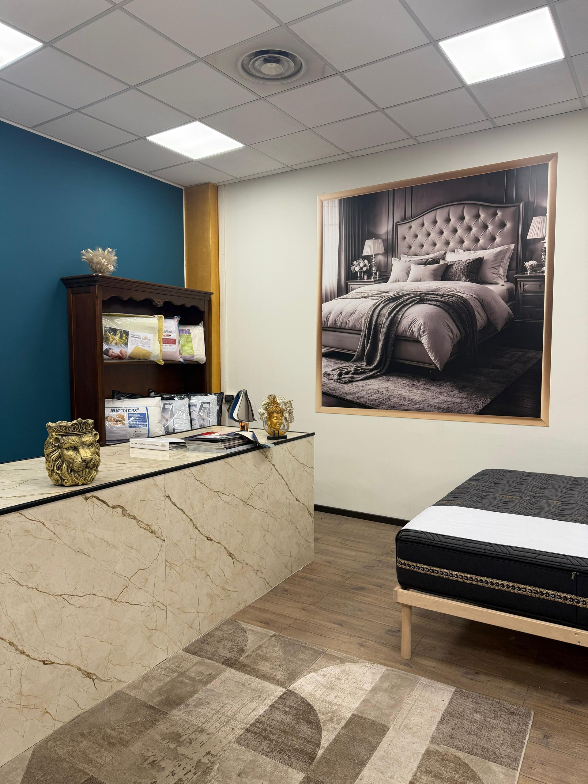 Showroom di materassi con esposizione di letti, scrivania e poster di una camera da letto.