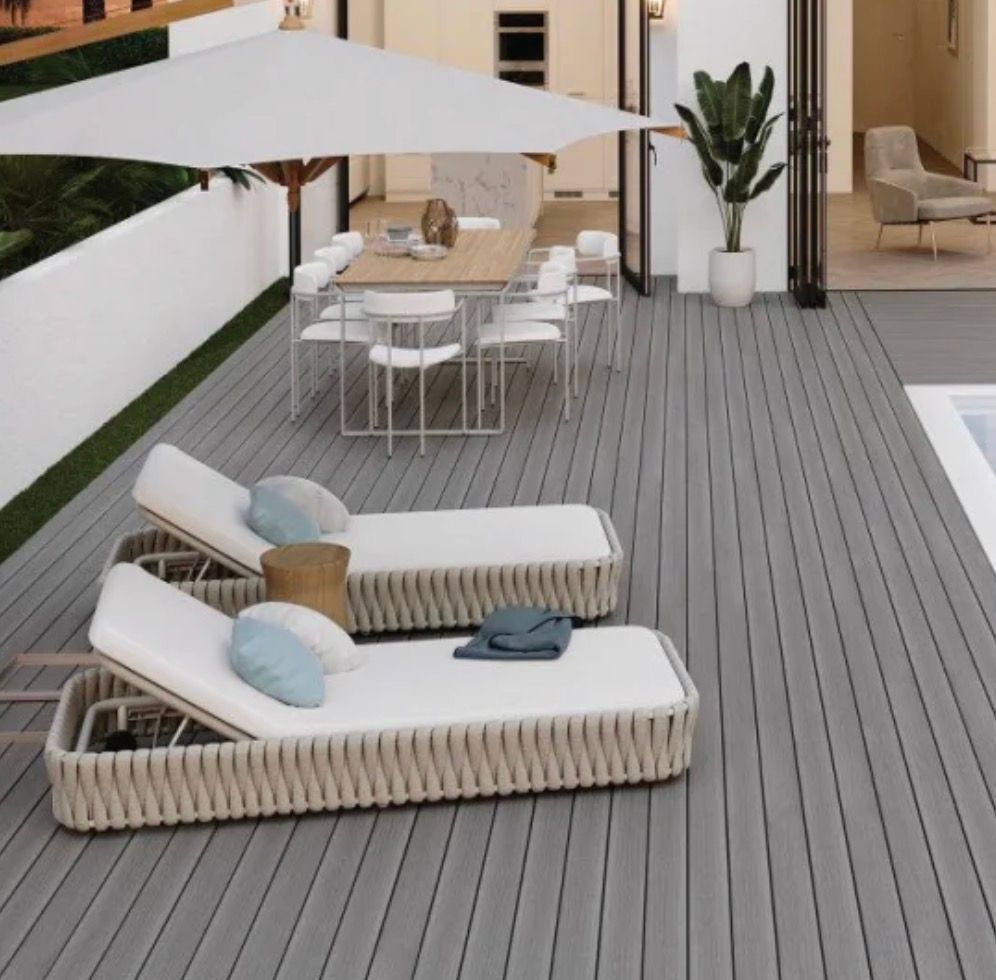 Outdoor deck with lounge chairs and dining table near a pool. Grey deck, white furniture.