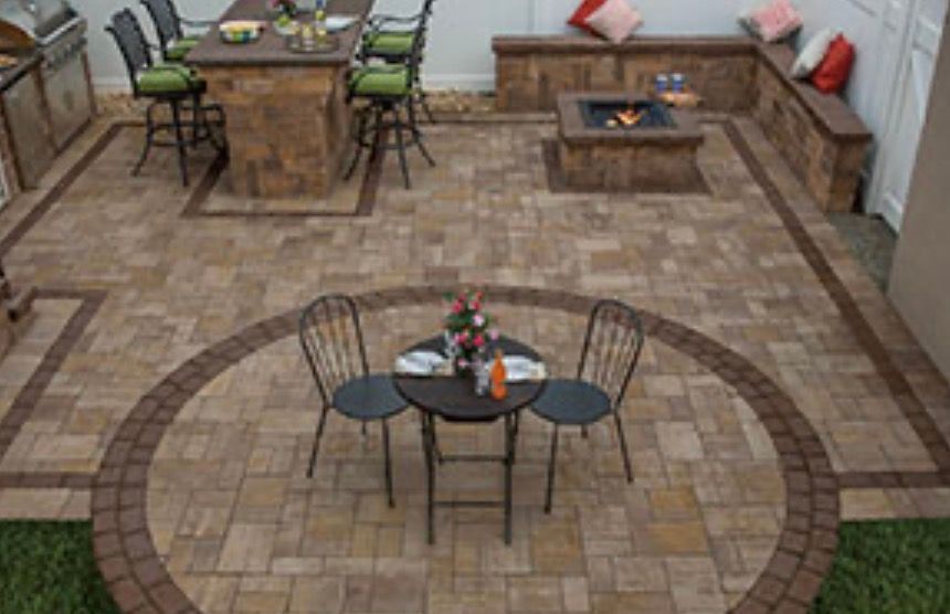 Outdoor patio with fire pit, bar, seating, and patterned pavers.