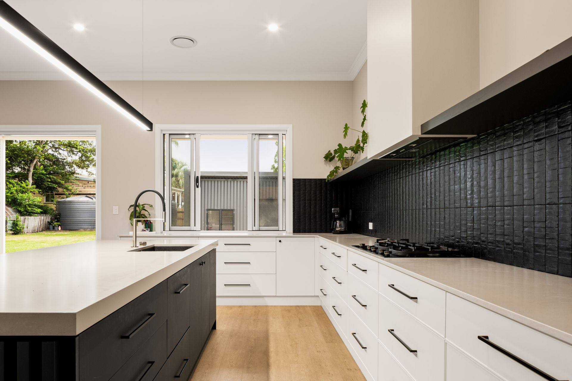 A Kitchen With a Large Island and White Drawers, wooden floor — Halls Cabinets & Joinery in Harlaxton, QLD