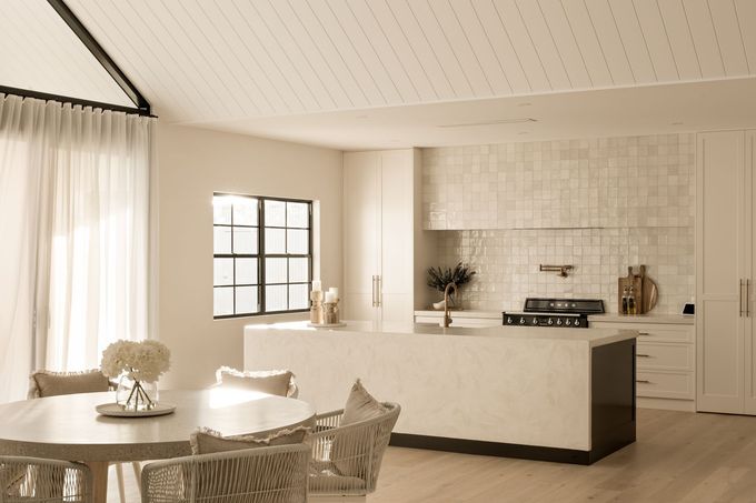 A Modern Kitchen With a Dining Table and Chairs and a Large White Kitchen Top — Halls Cabinets & Joinery in Harlaxton, QLD
