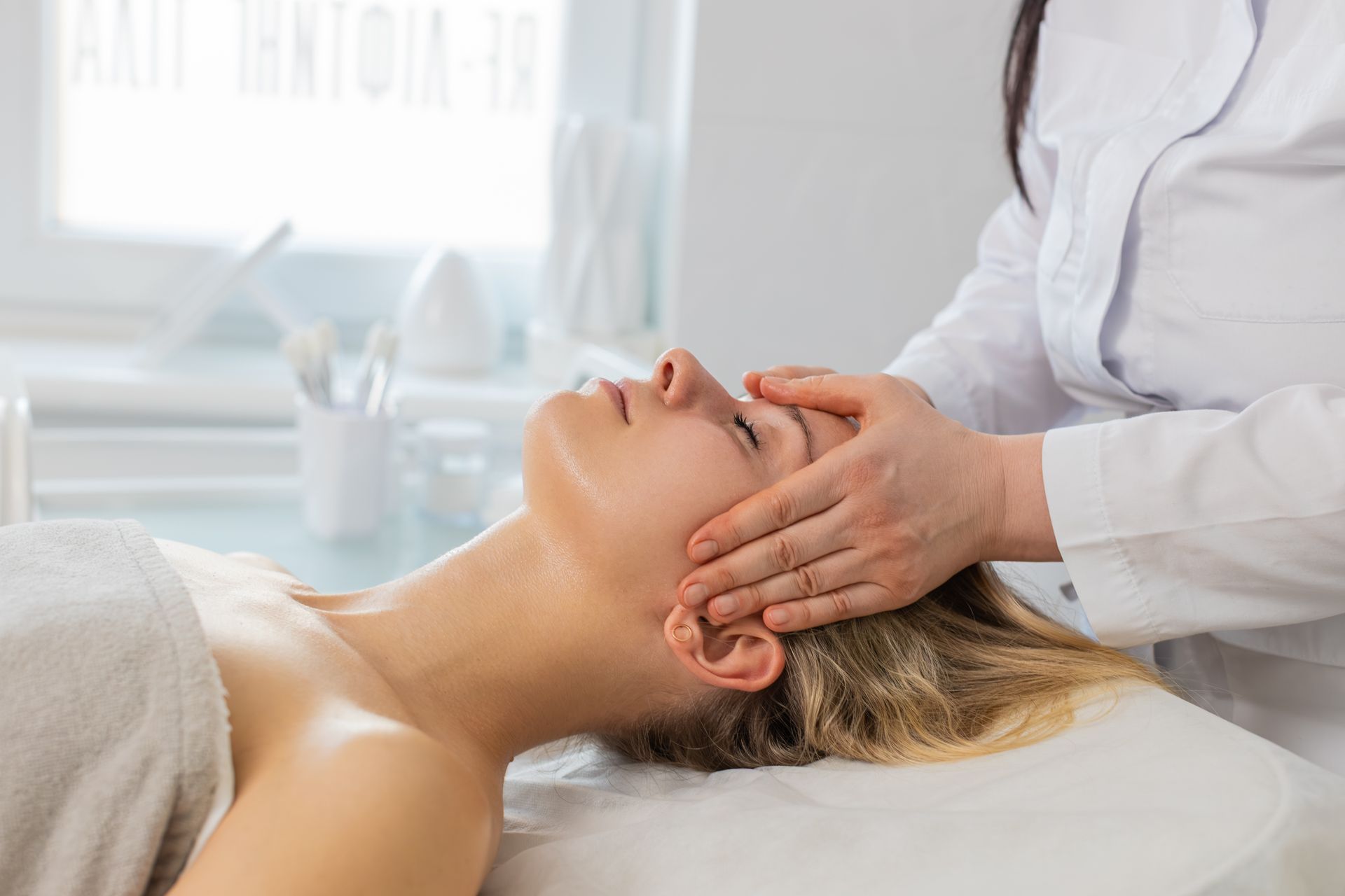 A person lies relaxed on a massage table receiving a back massage, overlaid with decorative white snowflakes and trees.