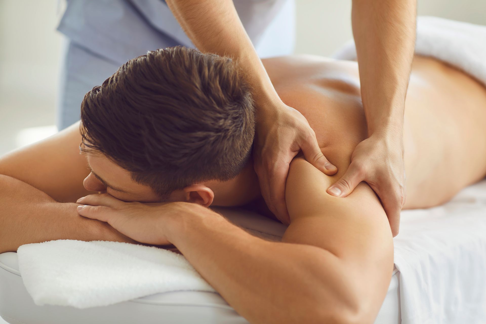 A person lying face down wearing a white towel, getting a medical massage.