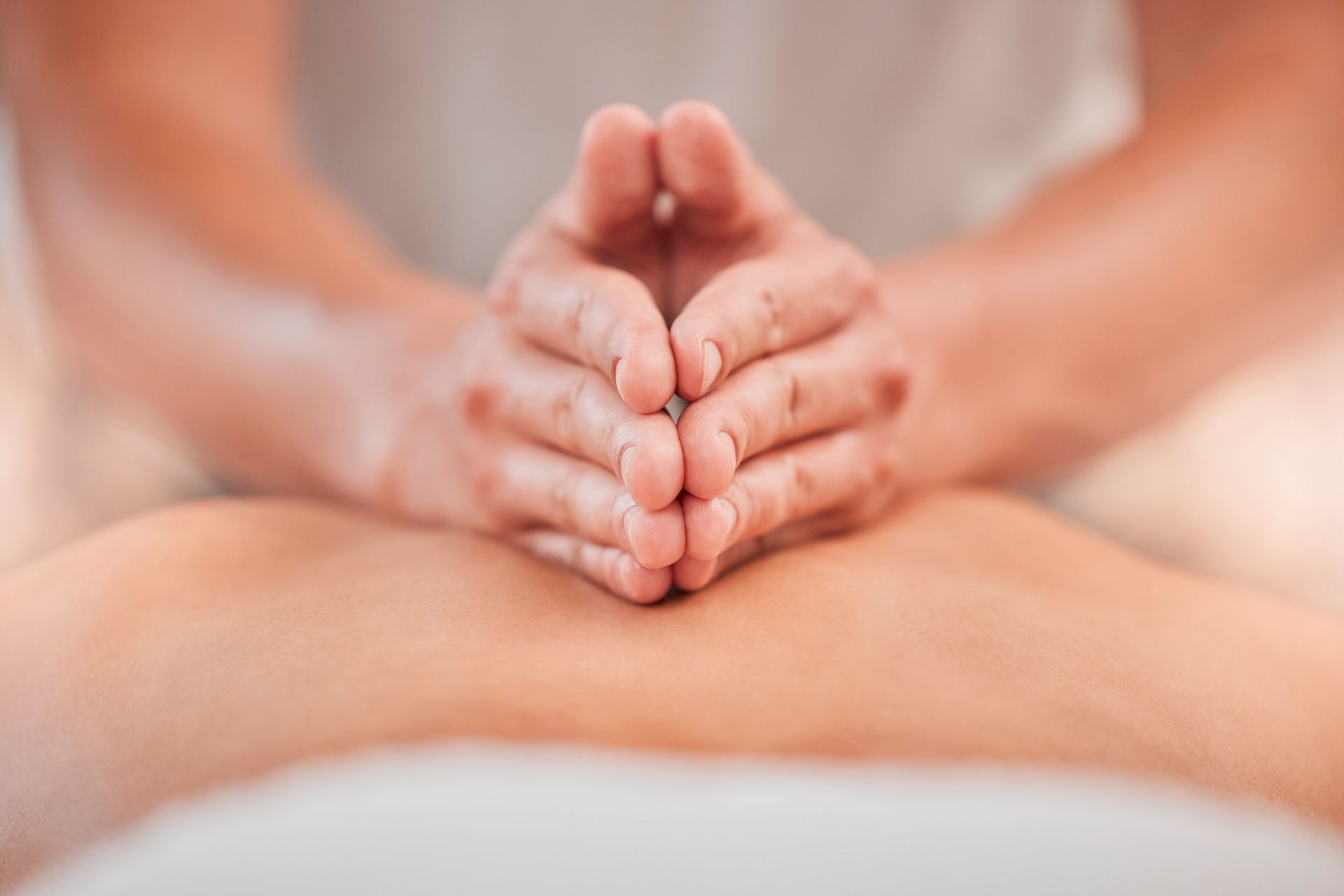 A close-up view of hands performing a focused massage on a person's upper back.