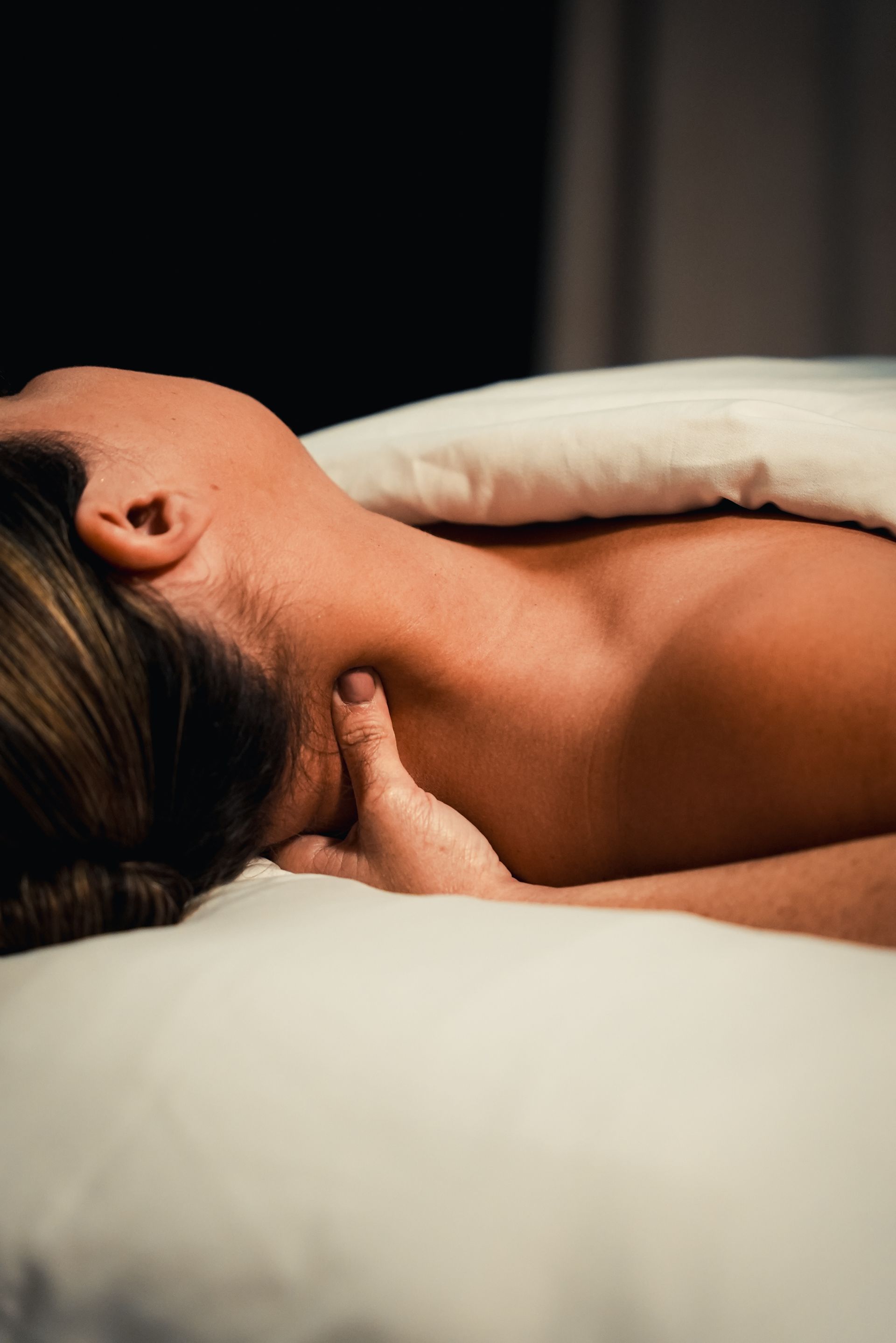 Close-up of a massage therapist applying pressure to a person's shoulder and upper back during a professional massage.
