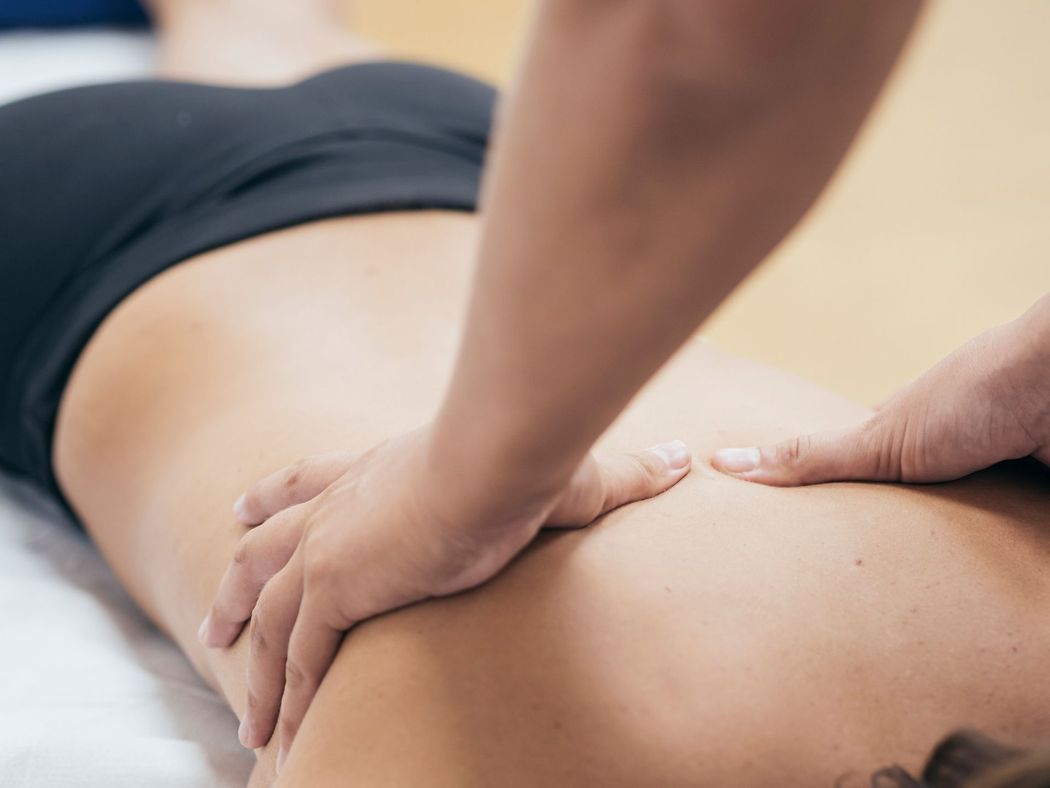A person receiving a massage on their back from a therapist in a clinical setting. A person receiving a massage on their back from a therapist in a clinical setting.