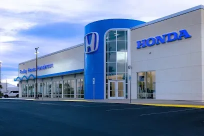 A white and blue honda car dealership with a parking lot in front of it.