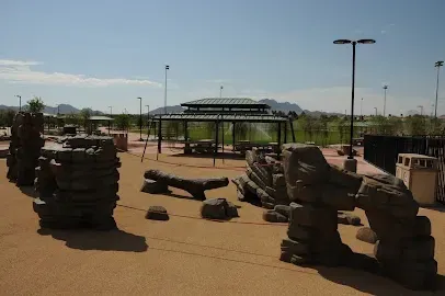 A playground with rocks and a gazebo in the background