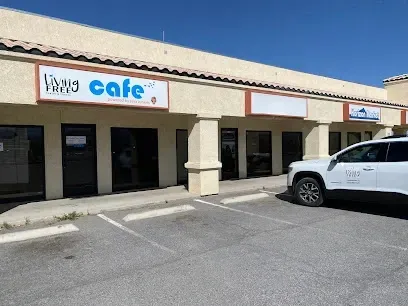 A white suv is parked in front of a building that says cafe.