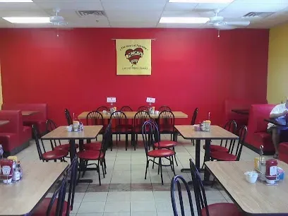 A restaurant with tables and chairs and a red wall
