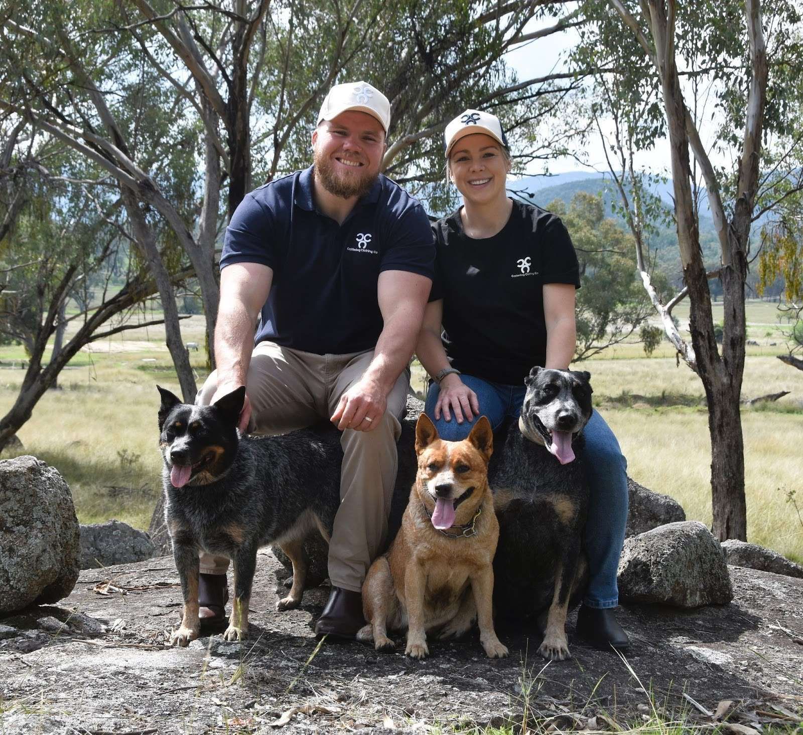 A man and a woman are posing for a picture with their dogs