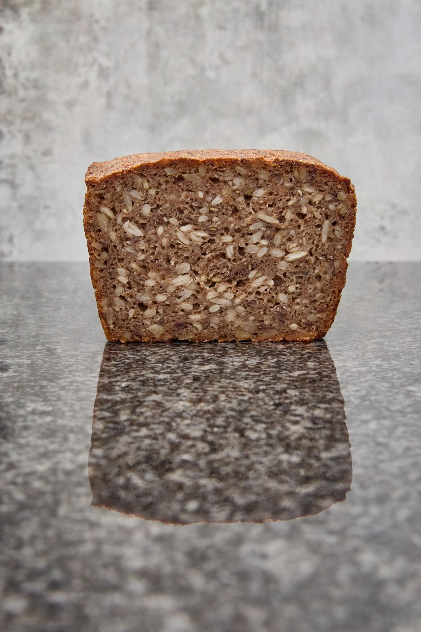 Surdejsbrød, sprødt og mørkebrunt på toppen, lysebrune sider, ridset med slidser på en træoverflade.