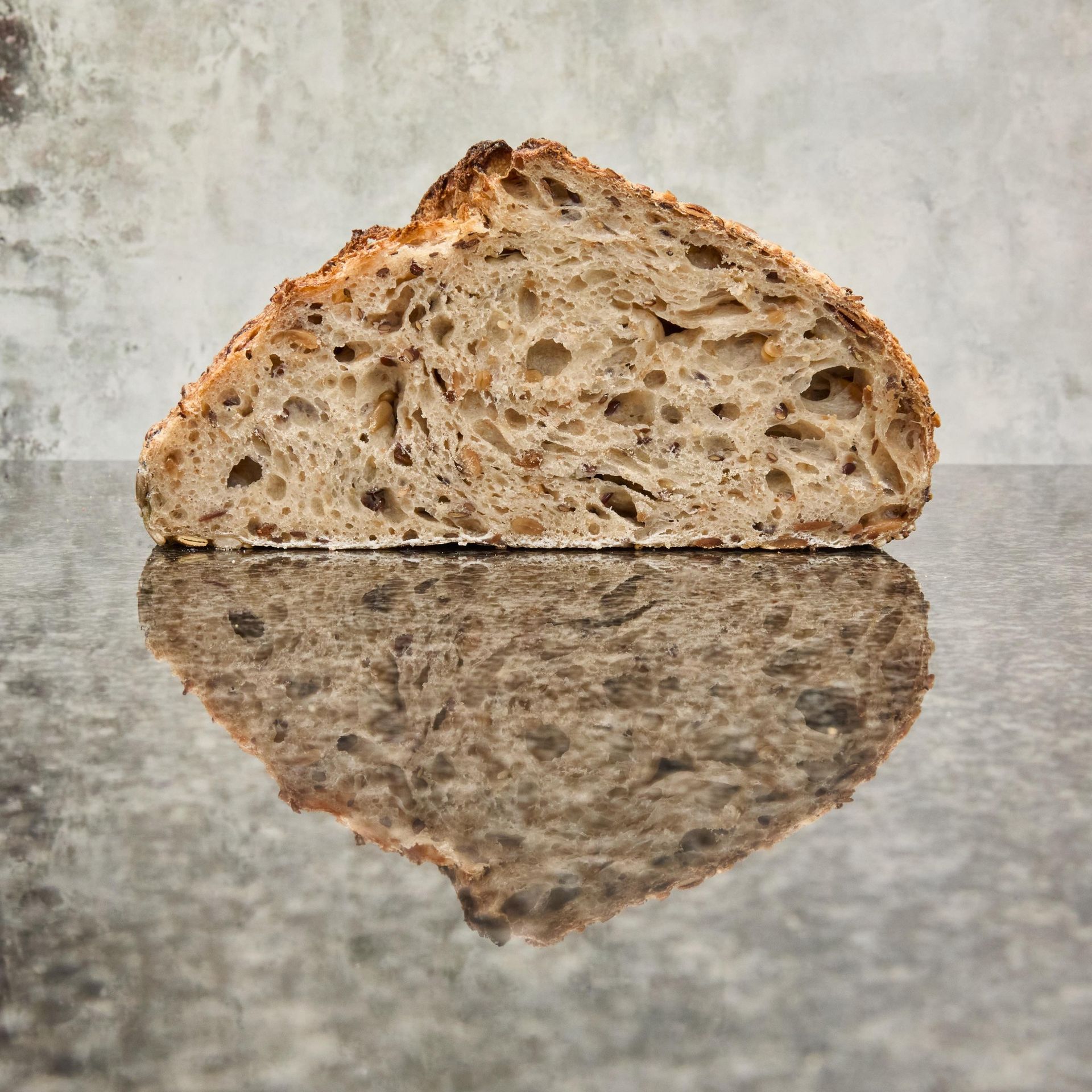 Hånd der holder et surdejsbrød med en mørk skorpe og rillet top.