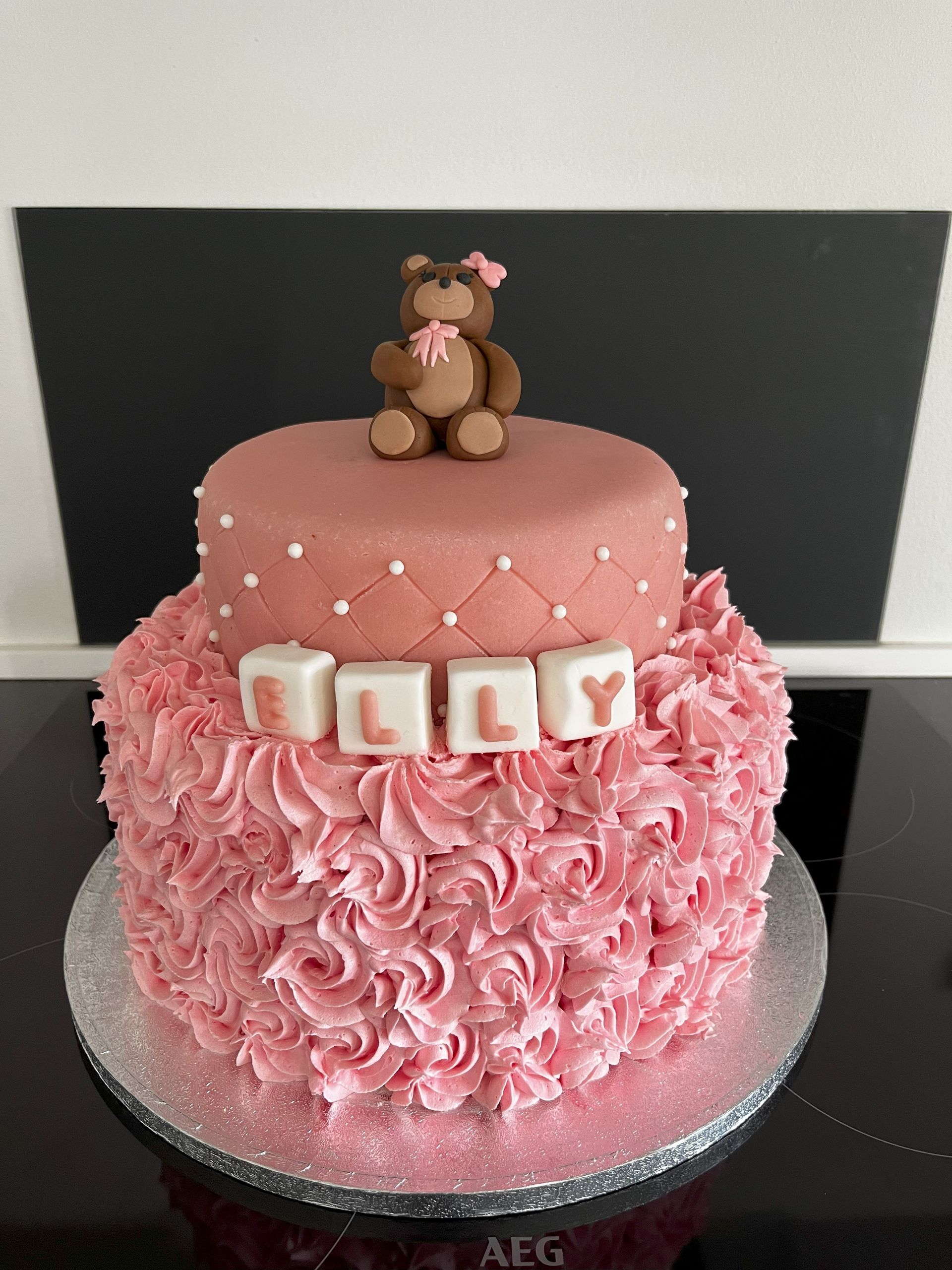 En lyserød kage med en bamse ovenpå.