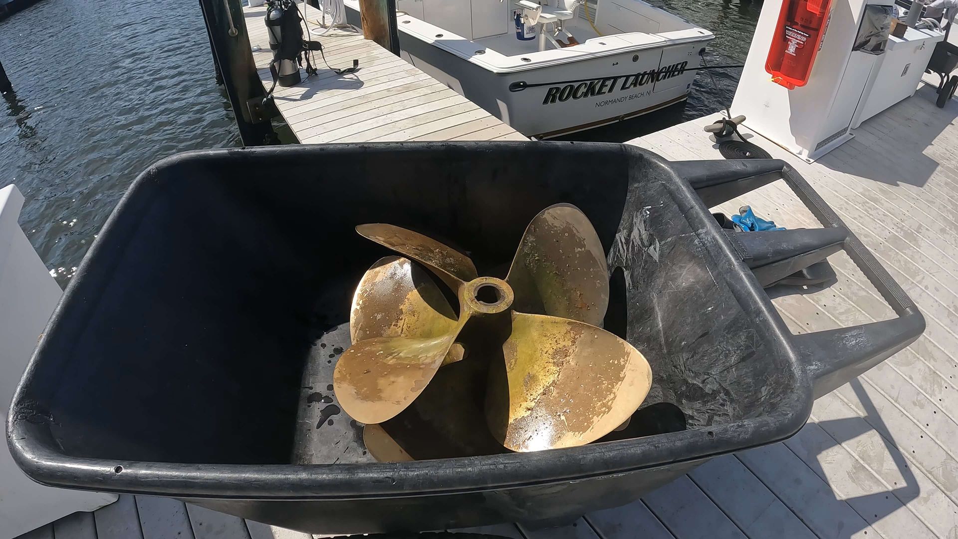 A boat propeller is in a wheelbarrow on a dock.