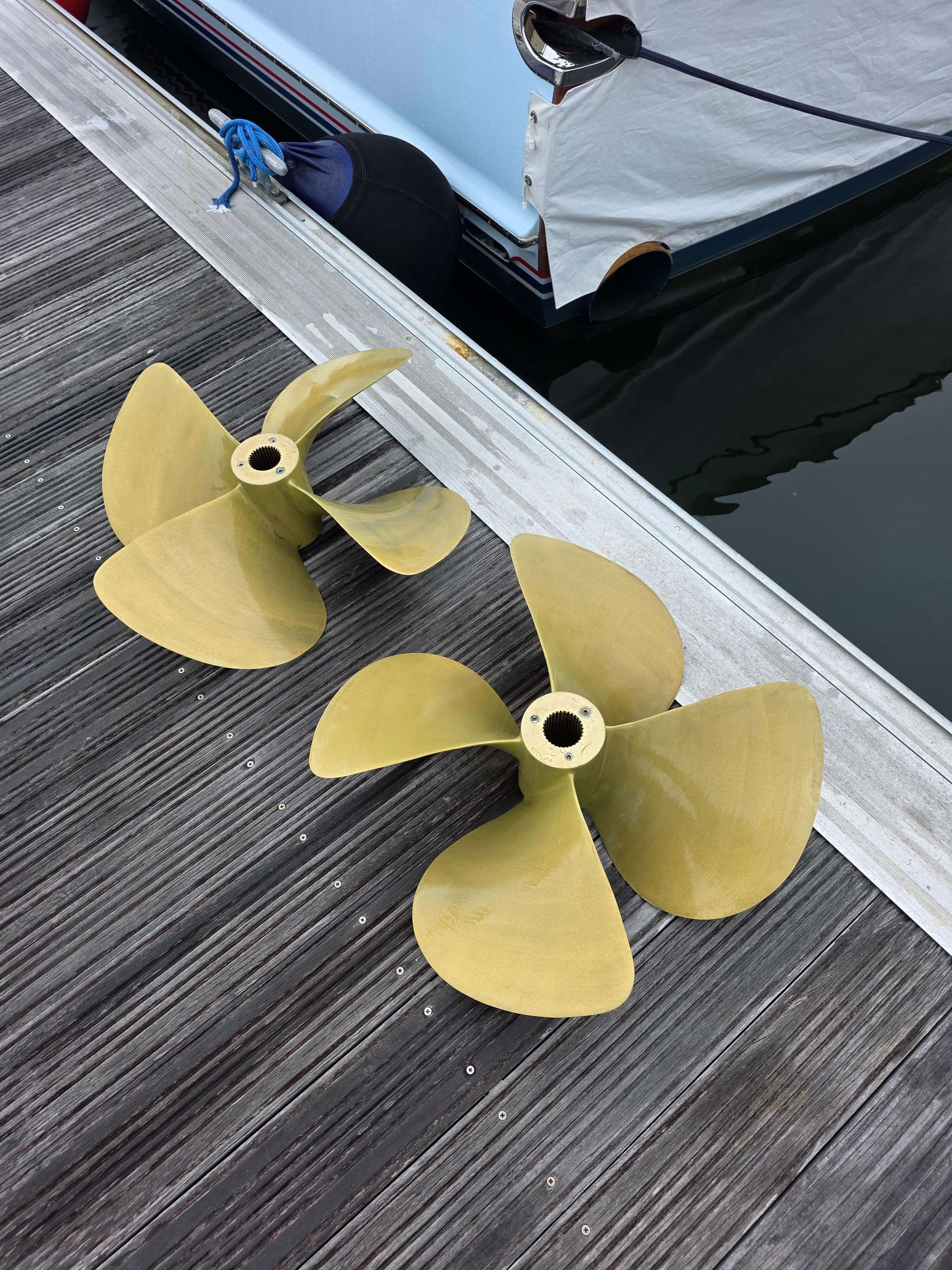 Two propellers are sitting on a wooden dock next to a boat
