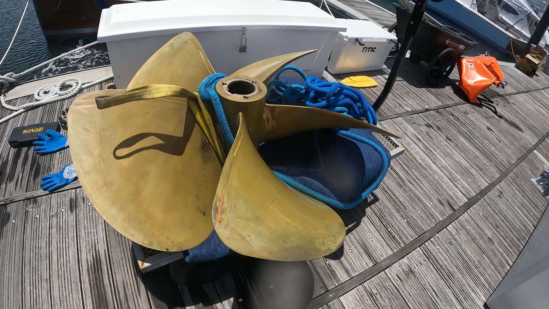 A large propeller is sitting on top of a wooden dock.