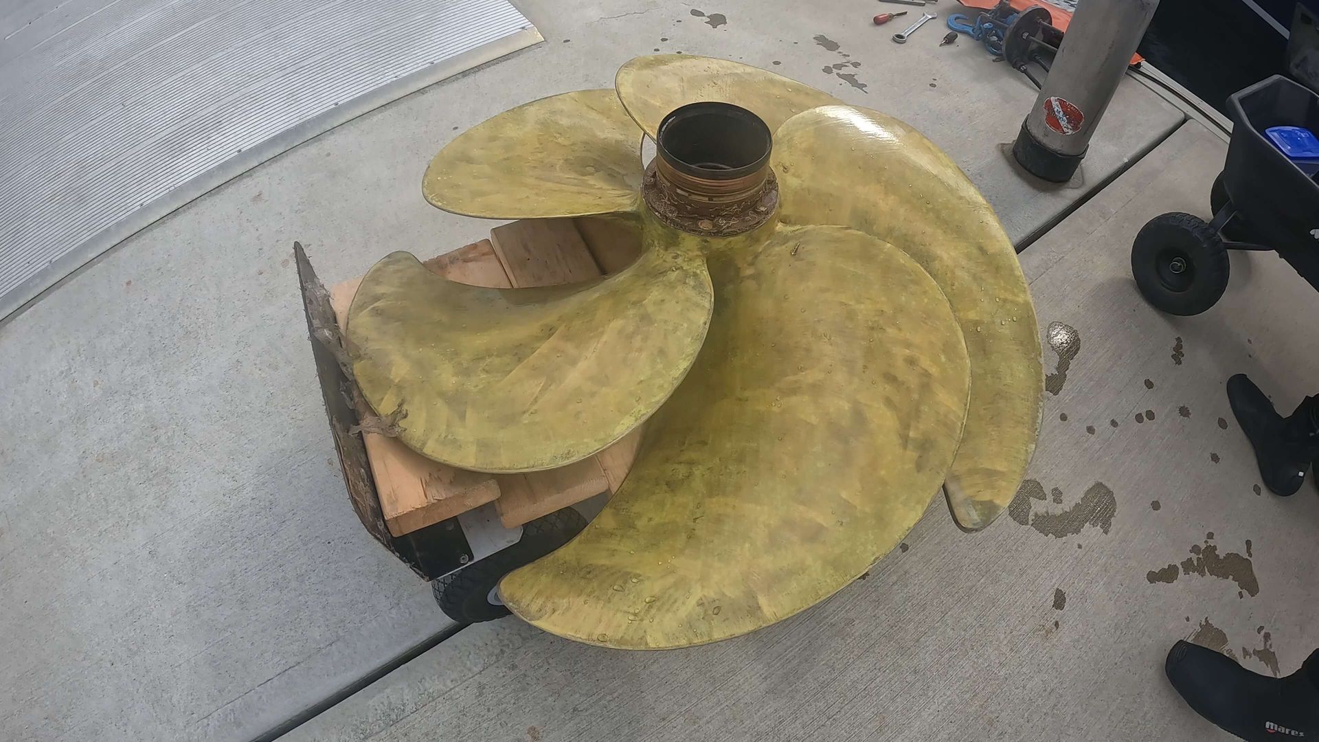 A large yellow propeller is sitting on a concrete surface.