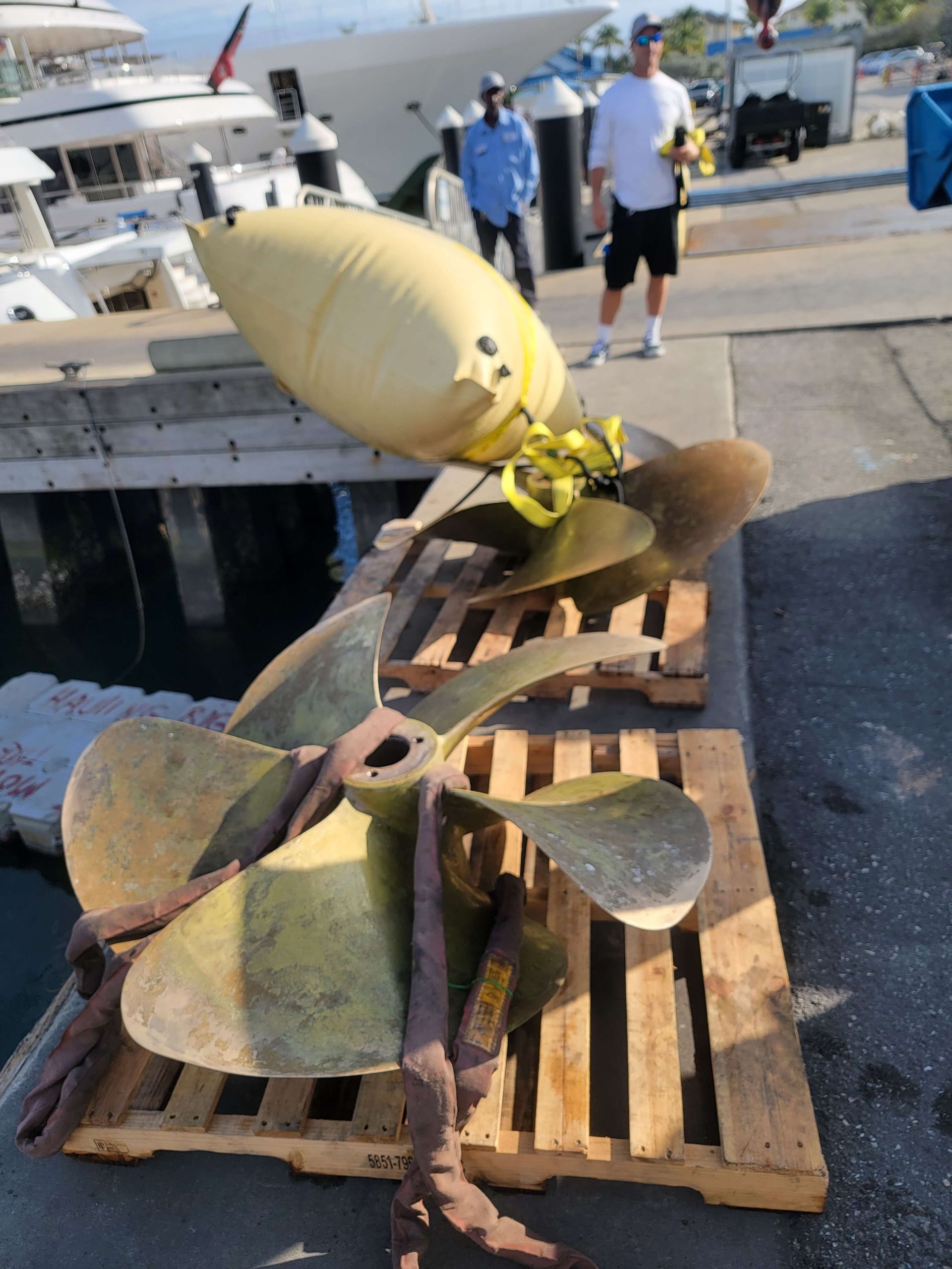 A man is standing behind a wooden pallet with propellers on it