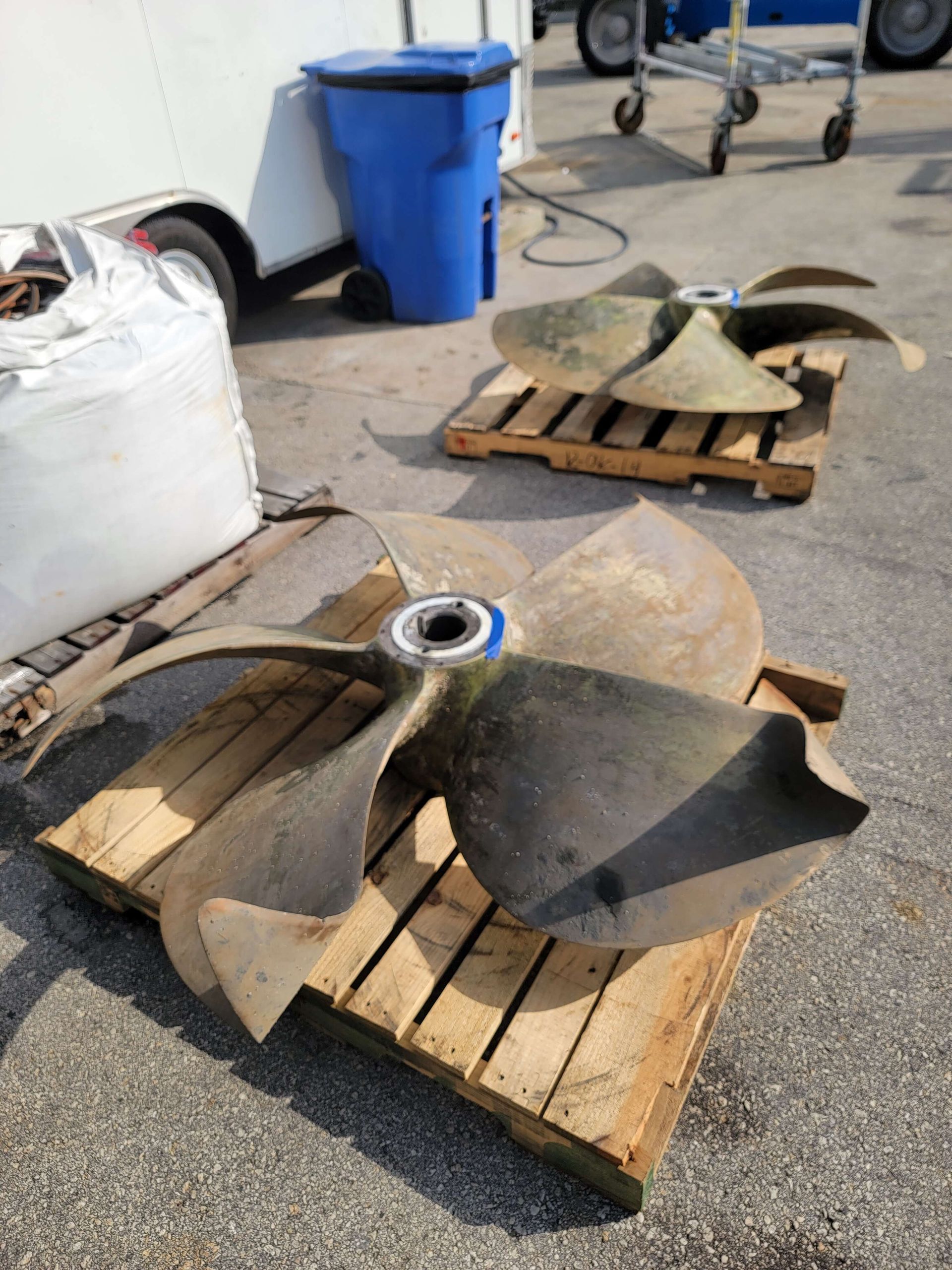 A man is standing behind a wooden pallet with propellers on it