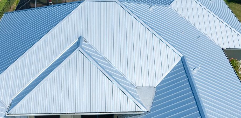 Close-up aerial view of a light blue metal roof with angled panels and ridges on a residential building.