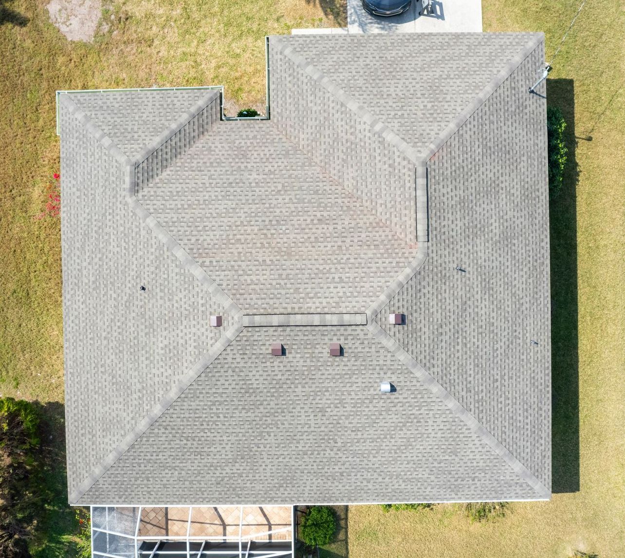 Overhead view of a gray asphalt shingle roof on a house surrounded by green grass.