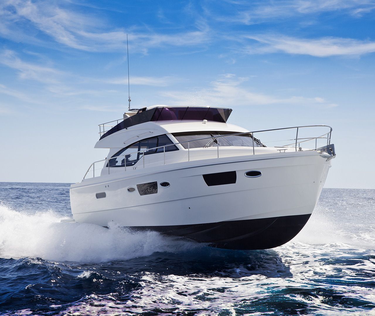White motorboat speeding on blue ocean under a partly cloudy sky.