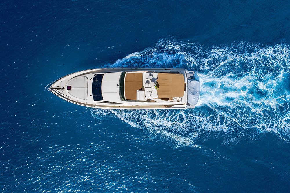 White motorboat moving across blue water, creating white wake.