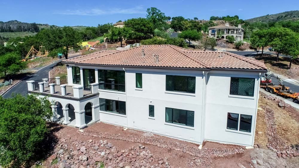 An aerial view of a large white house with a tile roof.