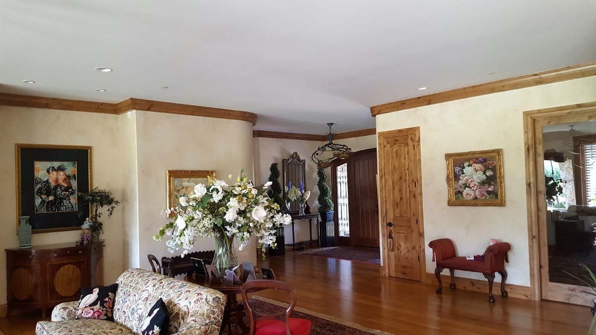 A living room with a couch , chairs and a vase of flowers.
