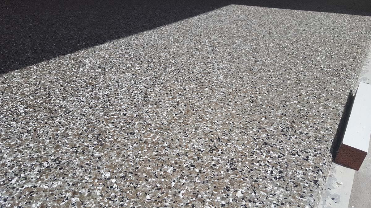 A close up of a concrete floor with a lot of small stones on it.