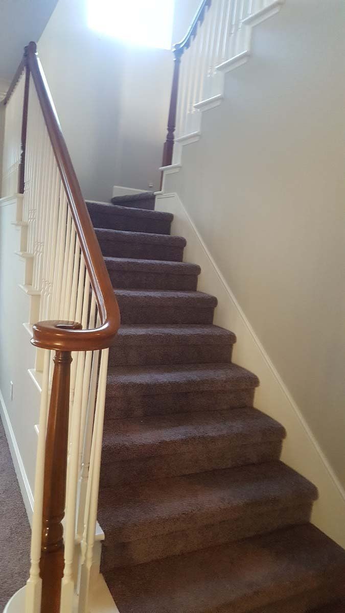 A staircase with a wooden railing and carpeted steps in a house.