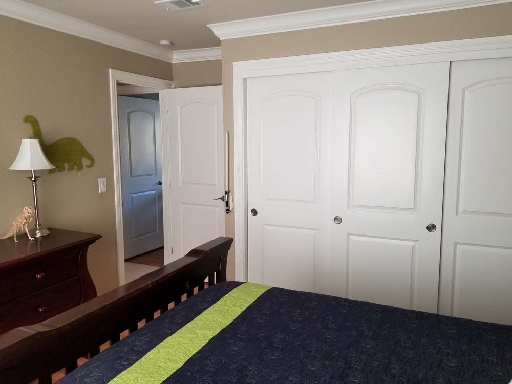 A bedroom with a bed and closets and a lamp
