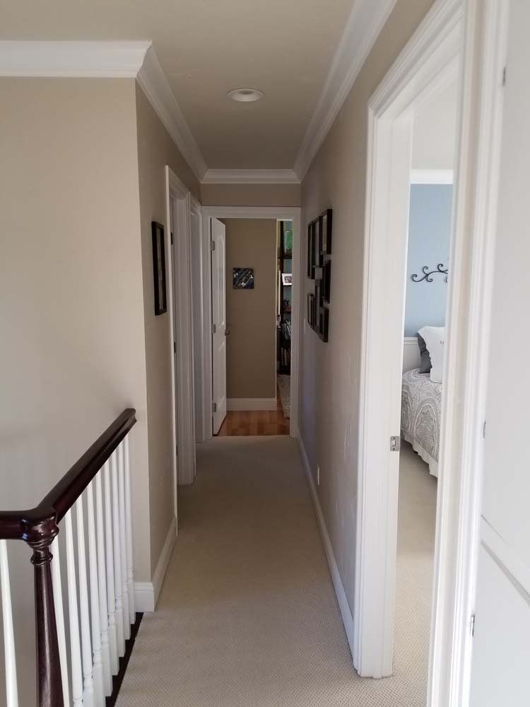 A long hallway with a railing leading to a bedroom
